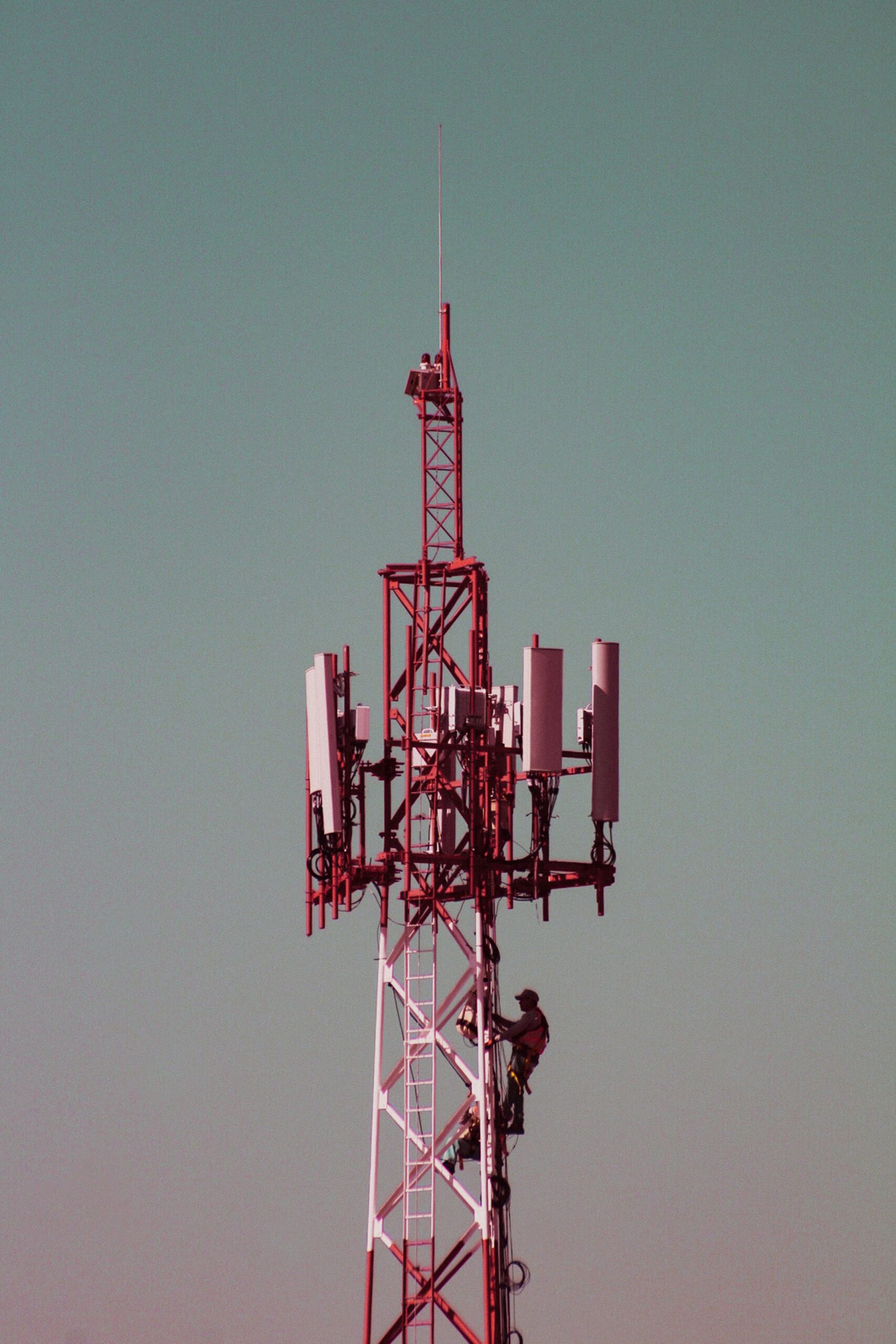 Tehnician telecom urcând pe un turn cu echipament de siguranță